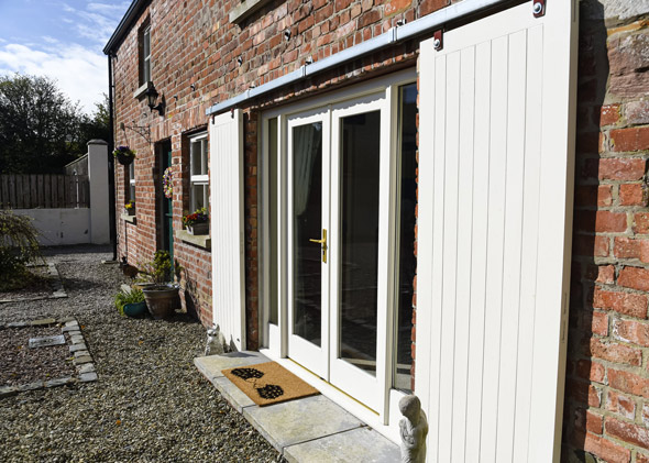 two stylish doors leading to a charming gravel pathway surrounded by greenery and a cozy atmosphere