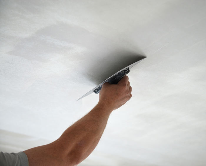 A man plastering a ceiling